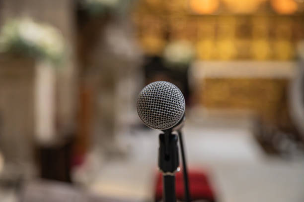 istock Microphone in the foreground ready to be used inside a church or religious space. Blurred church background. 1708339725