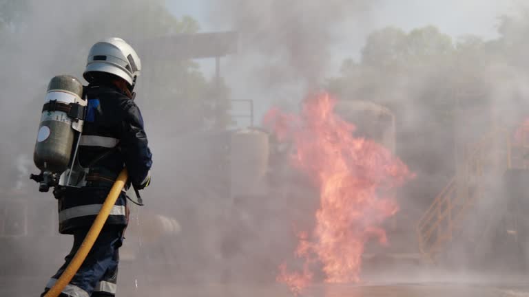 Professional Firefighters using fire hose extinguishing burning fire.