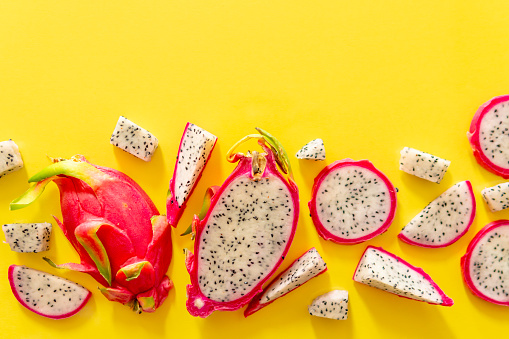 Slices of fresh white pitaya or dragon fruit on yellow background, flat lay. Concept of exotic tropical and vegan food.
