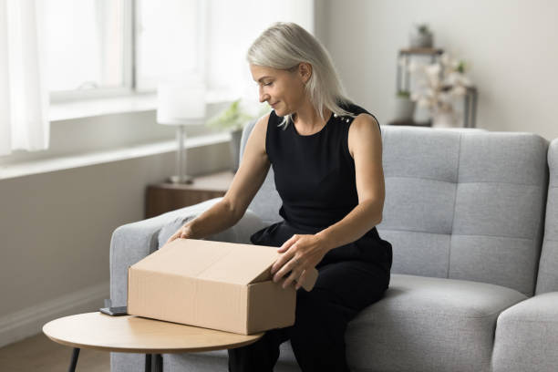 istock Positive blonde senior woman packing parcel for sending 1708362710
