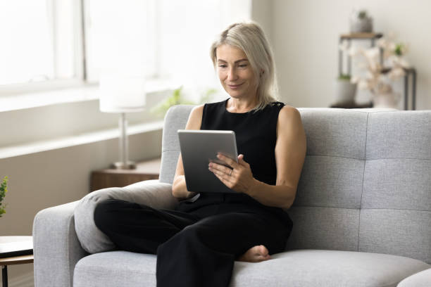 istock Positive blonde mature woman using online application on tablet 1708362737