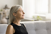 Happy relaxed mature woman enjoying fresh air, smells, relaxation