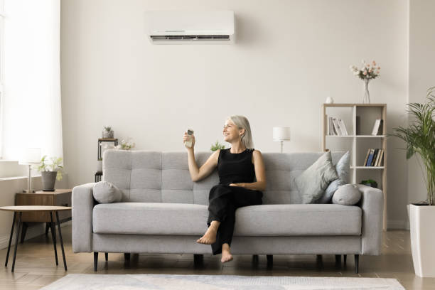 istock Happy positive mature woman using AC remote control 1708362770