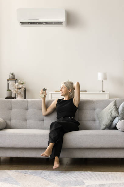 istock Happy relaxed middle aged woman starting air conditioner 1708362782