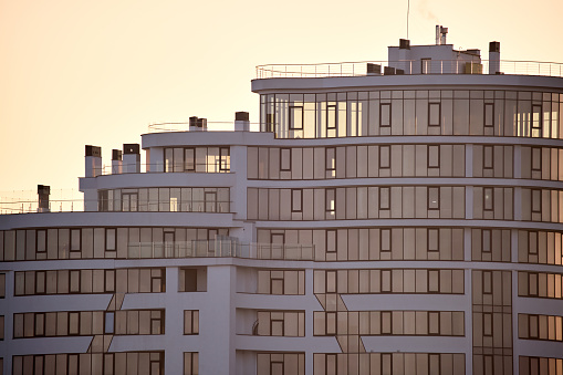 Architectural details of modern high apartment building facade with many windows and balconies.