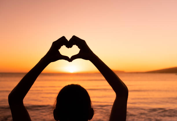 istock Woman making heart symbol against a beautiful sunset. 1708407613