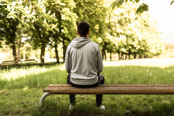 istock Man sitting on bench in the park. 1708422287