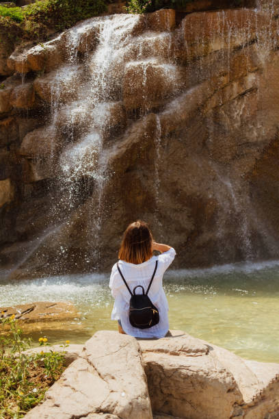 istock Woman sitting on a rock near a waterfall 1708463363