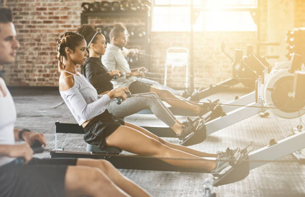 istock Rowing machine, group and training in gym, class or fitness workout, exercise or cardio, row team and practice. People, healthy athlete and challenge on sport equipment, row crew and sports club 1708463373