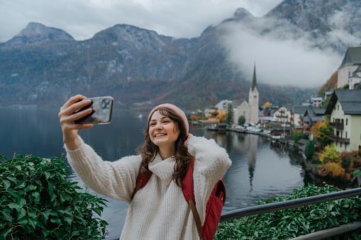 Cheerful woman making selfie with smartphone In Hallstatt