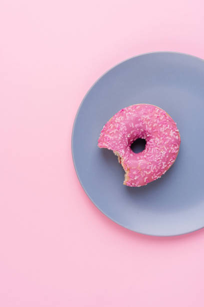 istock Top view of one pink donut on a plate on pink background 1708468614