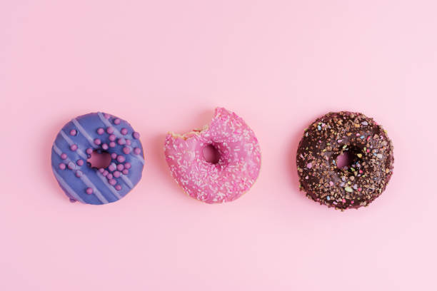istock Three colorful donuts on a pink background, copy space 1708469158