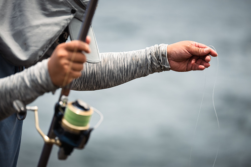 With a purposeful gesture, a man retrieves his fishing line, embodying the rhythm of a fisherman's pursuit. This simple act speaks of diligence and dedication in the timeless quest for the day's catch, where the connection between angler and aquatic world is reaffirmed.