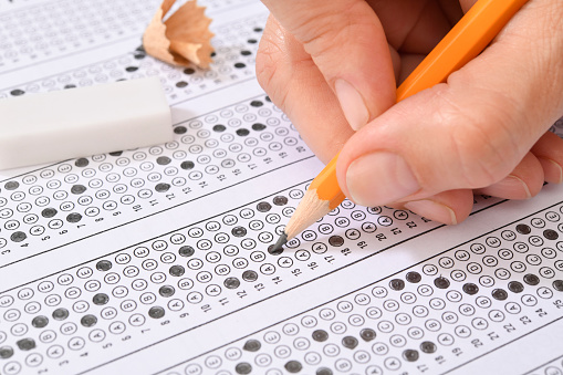 Student filling out answers to a test with orange pencil close-up