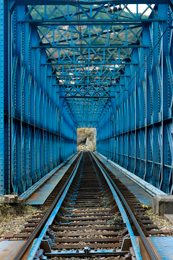 Perspective front view of the train tracks, on an iron bridge over the Miño River in Orense, Spain