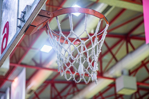 basketball hoop close-up. The basketball hoop with net and the lights of the basketball hall are visible. Red colored crucible.