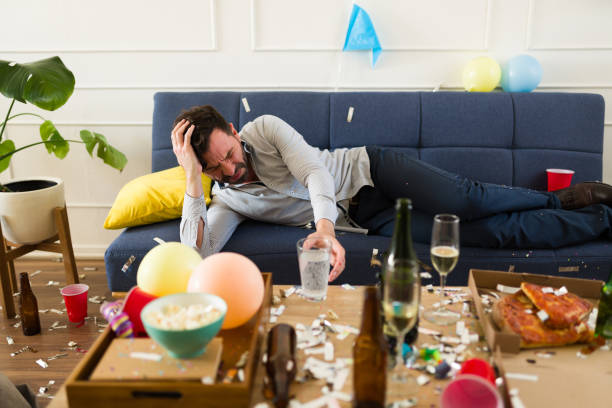 istock Hungover man with a headache waking up in the mess after a party 1708557556