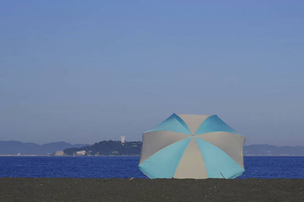 Enoshima and beach umbrellas.Coast of Chigasaki City, Kanagawa Prefecture, Japan.