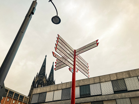 Cologne, Germany, July 23, 2023 Directional landmarks sign pointing to area attractions in Cologne, Germany. The majestic Cologne Cathedral stands tall in the background of view.