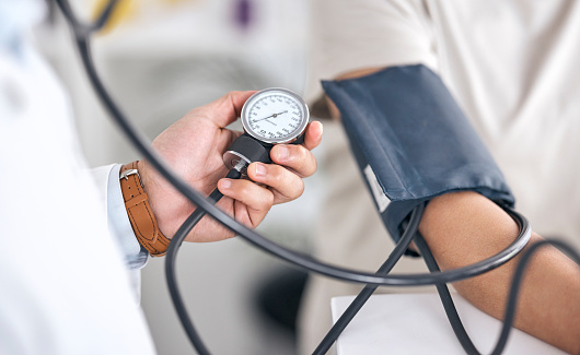 Hands, blood pressure and doctor with patient in consultation at hospital in clinic test. Stethoscope, exam and arm of person with medical professional for check up for heart health, advice and care.