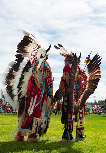 Two Native American Men in Full Regalia talking at the Little Shell Chippewa Pow Wow in Great Falls, Montana. Photographed from a low angle view.