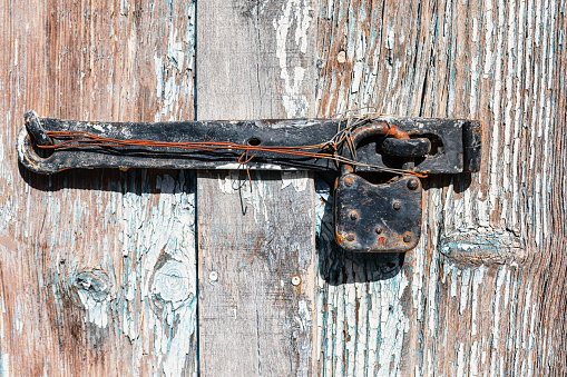 Old rusty hinge on a weathered wooden door. Shallow depth of field