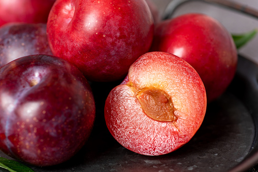 Whole and sliced red plums, close up