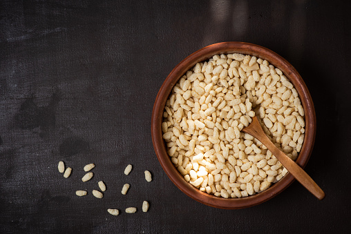 Brown bowl of rice crispy and cup of milk on rustic background