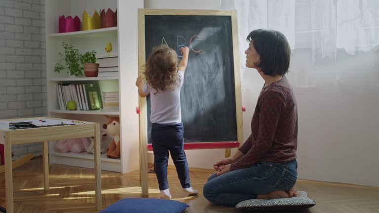 Mother teaching child to write letters