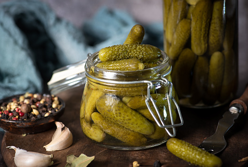 Green pickle cucumbers in a glass jar. Natural product on black -gray background. Top view