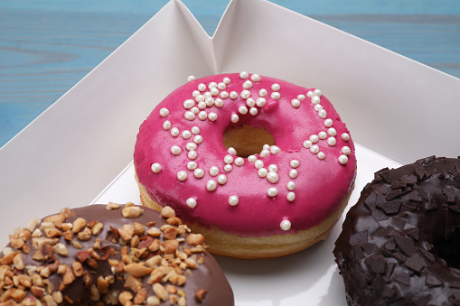 Different tasty glazed donuts in box, closeup