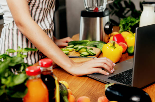 istock Female hand using laptop at kitchen. Food delivery, mobile dieting app 1708871371