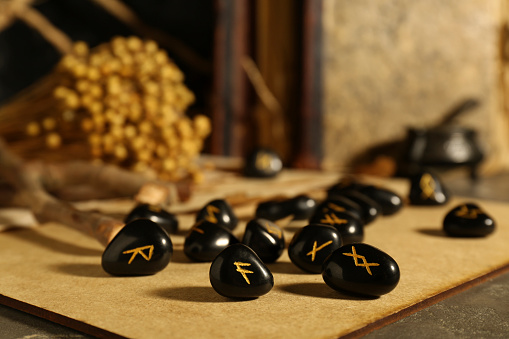 Wooden board with many black rune stones on table