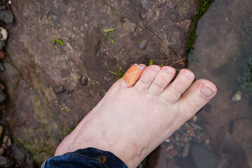 top view of left foot, barefoot, on rugged beach rock, small pale white woman's foot