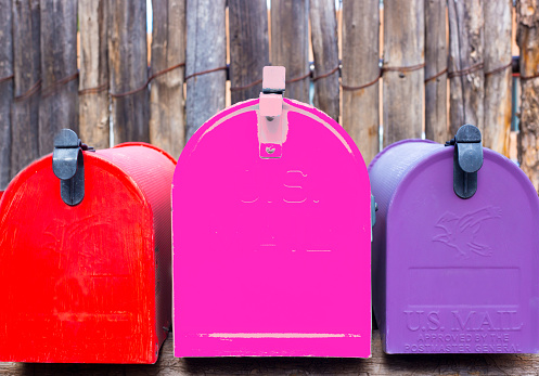 Three Vibrant Rural Mailboxes: Magenta, Red, Purple
