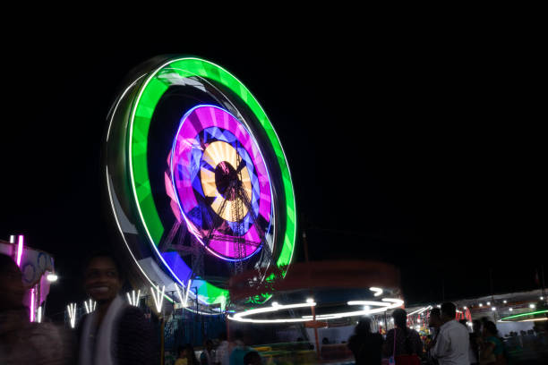 zdjęcie kolorowego poruszającego się gigantycznego koła podczas lokalnego podmiejskiego jarmarku. zabawa, świętowanie, ludzie, cieszyć się, przejażdżki, wioska, dzieci, festiwal, wydarzenie, �światła, park rozrywki - carnival spinning built structure frame zdjęcia i obrazy z banku zdjęć