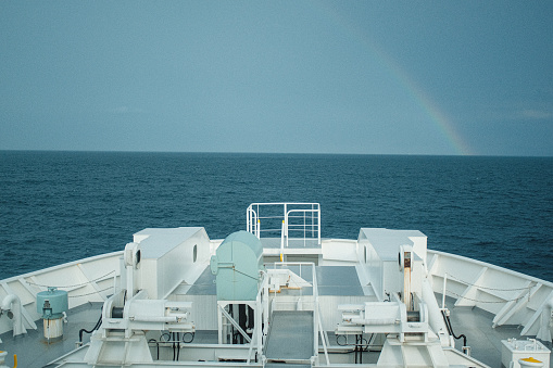 A rainbow appears in the sky behind the ship