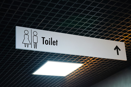 Public toilet sign with restroom symbol and arrow showing direction