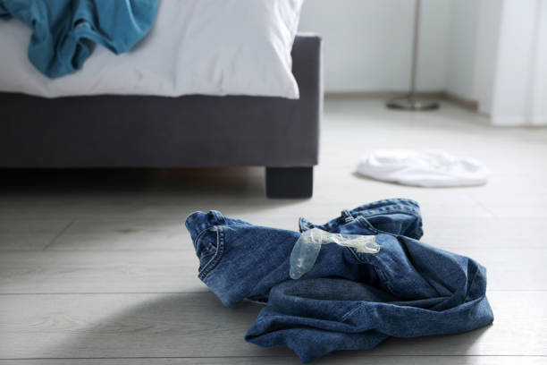 préservatif et jeans déroulés sur le sol dans la chambre. sexe sans risque - condom sex education contraceptive aids photos et images de collection