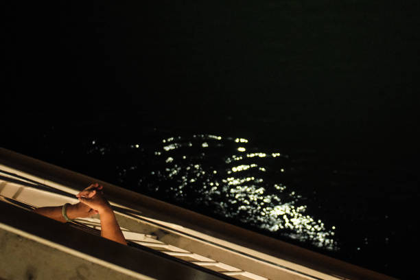 Onboard a sailing vessel, two hands extend over the railing, pondering the vast expanse of the sea, embodying the contemplative spirit of seafaring adventures.