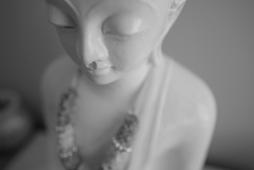 closeup portrait of antique damaged stone bust statue depicting a woman head with large pieces missing from the face area and large cracks in the marble