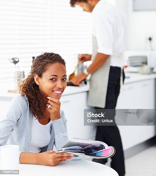 Foto de Feliz Jovem Mulher Lendo Uma Revista Com Seu Marido e mais fotos de stock de Adulto