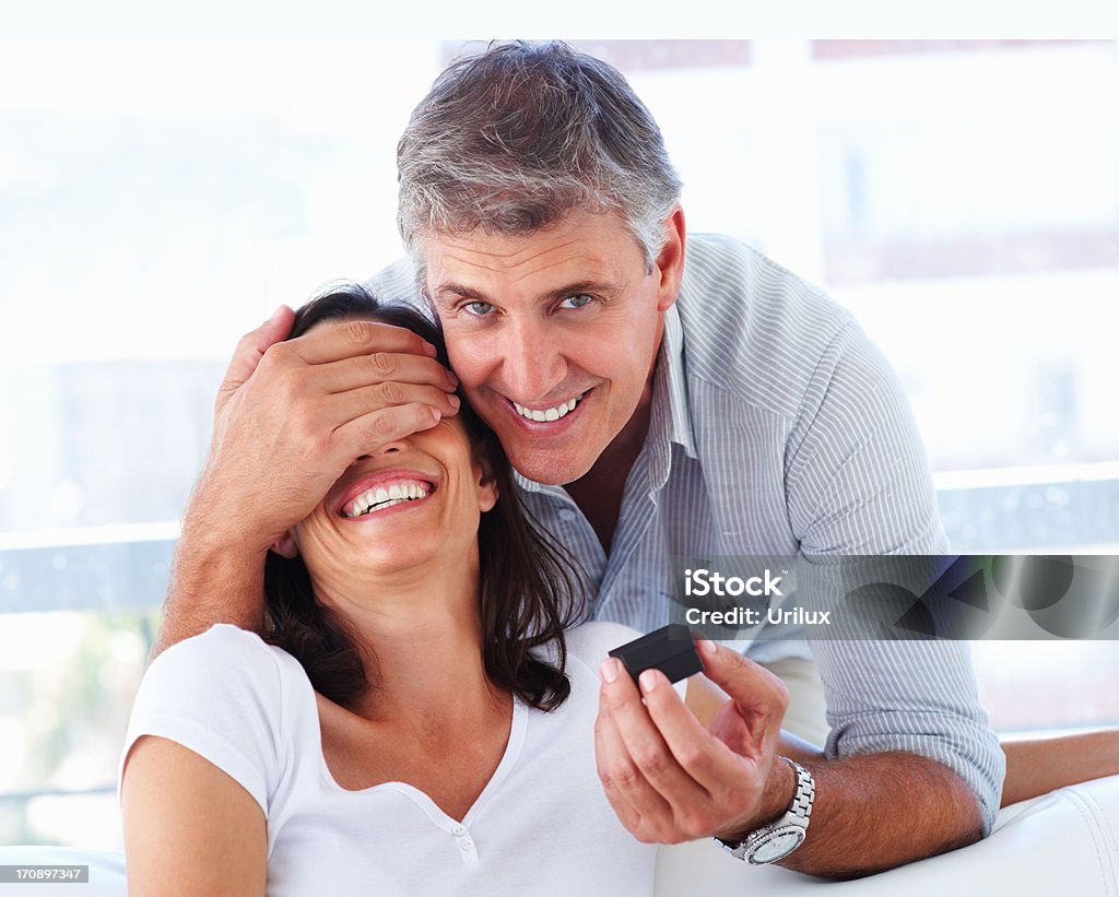 Dojrzały mężczyzna obejmujące jego oczy żony do Niespodzianka jej - Zbiór zdjęć royalty-free (Człowiek dojrzały)