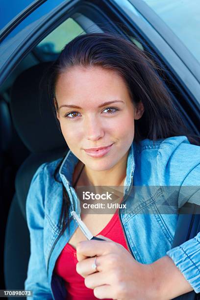 Sonriente Joven Mujer Sentada En Un Coche Y Llave De Retención Foto de stock y más banco de imágenes de Adulto