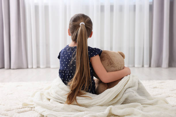 istock Cute little girl with teddy bear at home, back view 1708983944