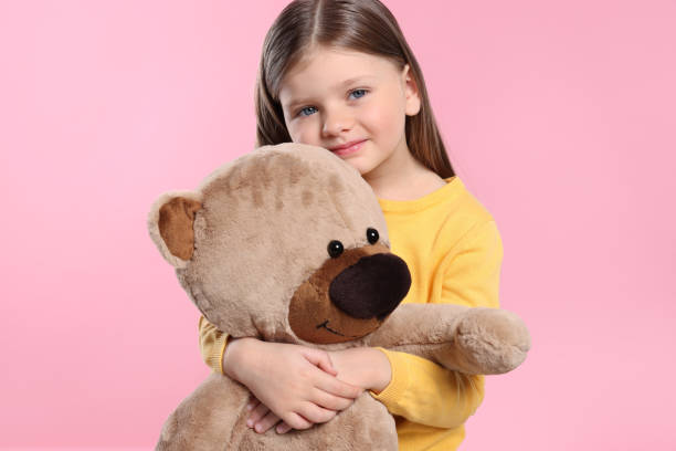 istock Cute little girl with teddy bear on pink background 1708986606