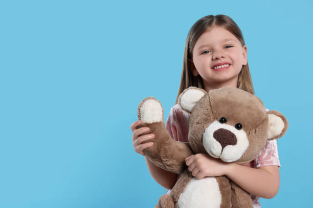 istock Cute little girl with teddy bear on light blue background. Space for text 1708986614