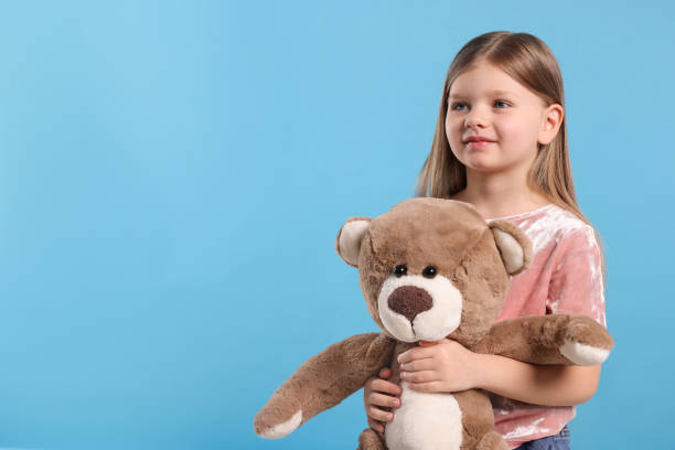 istock Cute little girl with teddy bear on light blue background. Space for text 1708986636