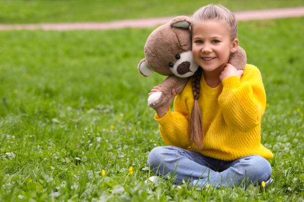 istock Little girl with teddy bear on green grass outdoors. Space for text 1708986796