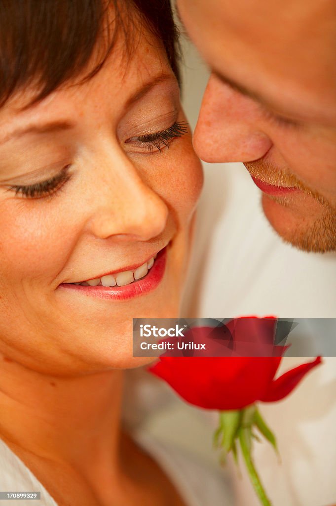 Una giovane coppia romantica godendo il profumo delle rose - Foto stock royalty-free di Abbigliamento casual